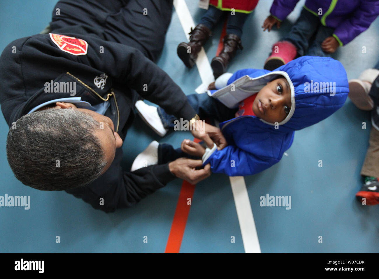 St. Louis Fire Department captain James Morgan helps Terrell McFee (2) with  the sleeves of his