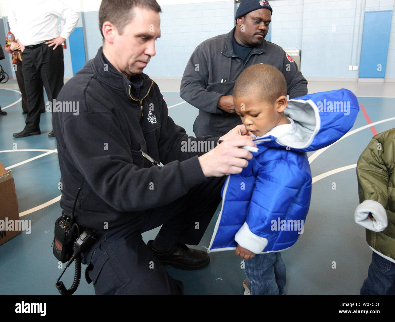 St. Louis Fire Department firefighter Jerald Scheen helps Terrell McFee (2) with his new jacket after receiving the coat at the Kingdom House in St. Louis on February 12, 2014. The Fire Department gave away 102 coats to all of the children at the day care center.  UPI/Bill Greenblatt Stock Photo