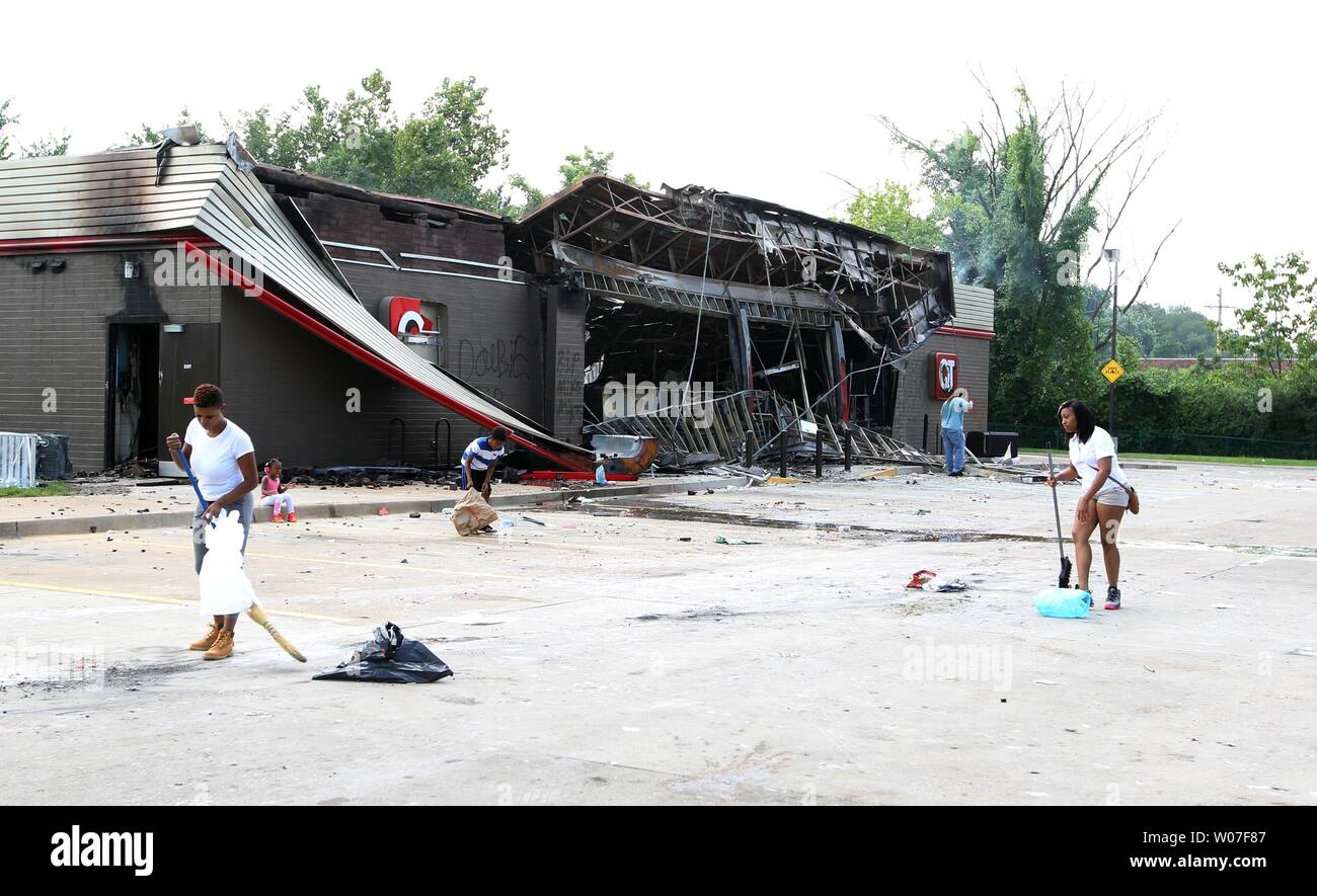 Volunteers clean up debris on the parking lot of a QuikTrip gas station after demonstrators looted and set fire to the building when a candlelight vigil became violent in Ferguson, Missouri on August 11, 2014. People are protesting the police shooting of the unarmed black teenager Michael Brown on August 9, 2014. UPI/Bill Greenblatt Stock Photo