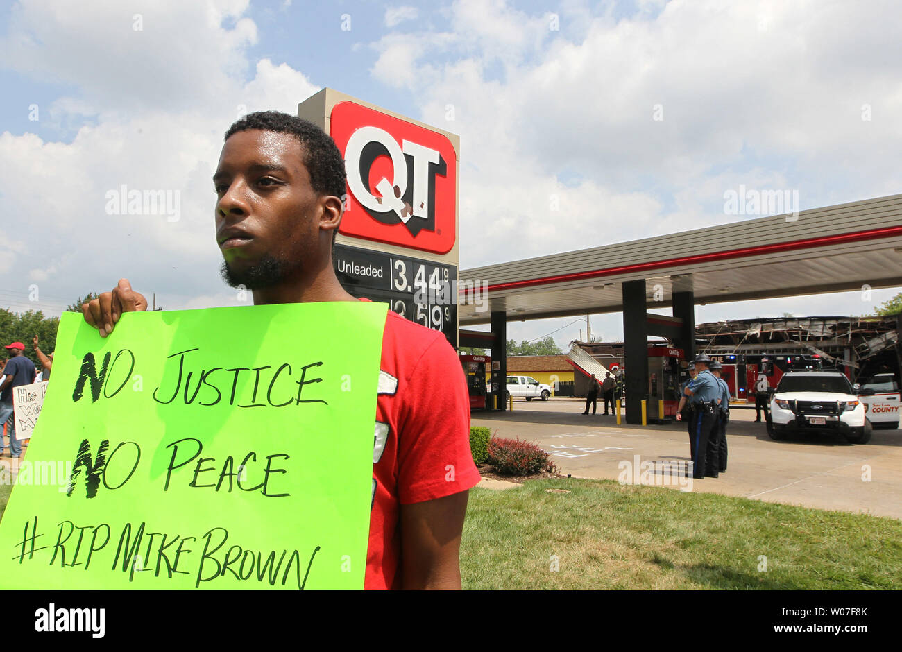Protestor Allen Smith holds his sign up for passing traffic as he stands outside of the QuikTrip Gas station that was burned after a night of looting, rioting and arsons in Ferguson, Missouri on August 11, 2014. People are upset because of the Ferguson Police shooting and death of an unarmed black teenager Michael Brown on August 9, 2014. In all about 20 businesses sustained damage after a candlelight vigil turned violent. UPI/Bill Greenblatt Stock Photo