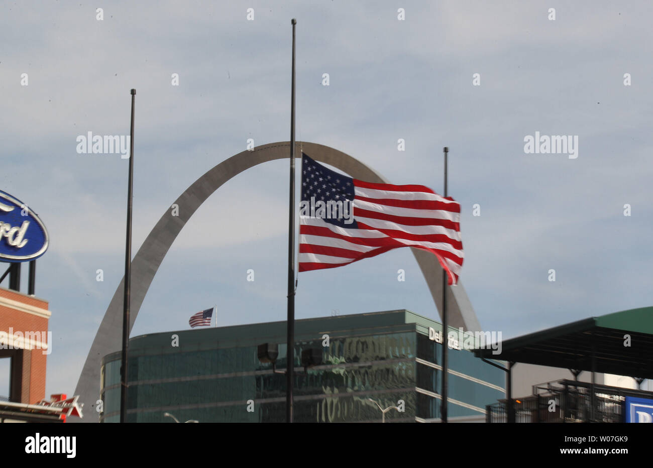 The American flag blows in the wind at half staff in the shadow of the Gateway Arch inside Busch Stadium in St. Louis on October 27, 2014. Fans have left flowers, candles, photos, baseballs and other mementos near the Stan Musial statue after word spread that Oscar Taveras, the Cardinals 22 year-old  rookie right fielder was killed in a car accident with his girlfriend in the Dominician Republic on October 26, 2014. Taveras hit a home run in the NLCS against the San Francisco Giants on October 12. 2014.  UPI/Bill Greenblatt Stock Photo