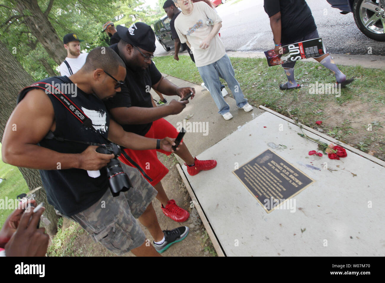 Visitors gather at a memorial to Michael Brown Jr. to take photographs  before a ceremony marking the one year anniversary that touched off weeks  of violence and riots in Ferguson, Missouri on