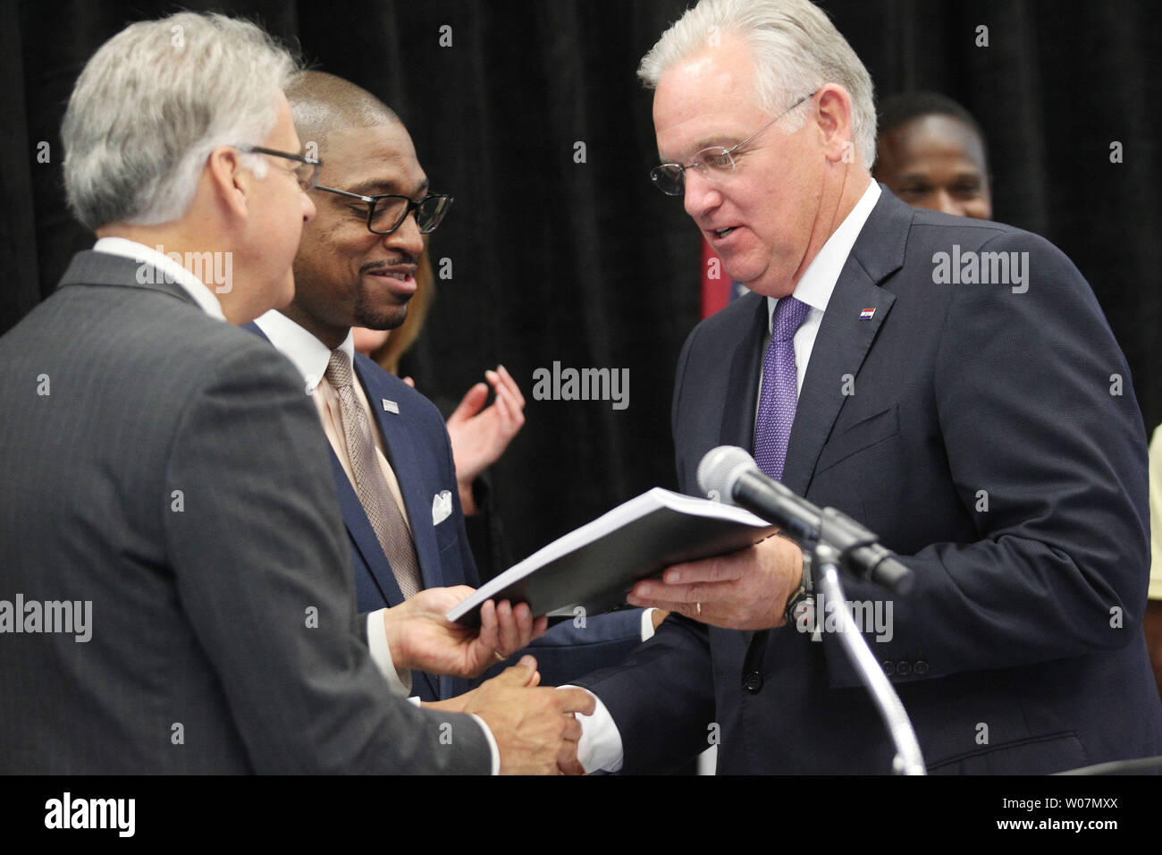 Missouri Governor Jay Nixon (R) accepts a copy of the Ferguson Commission's recomendations from co-chairs Rich McClure (L) and Rev. Starsky Wilson during a press conference in Florissant, Missouri on September 14, 2015. The Ferguson Commission was assembled by the Governor last November to discuss and recommend changes following the volence and looting that occured in Ferguson, Missouri following the shooting death of Michael Brown by white Ferguson police officer Darren Wilson.    Photo by Bill Greenblatt/UPI Stock Photo