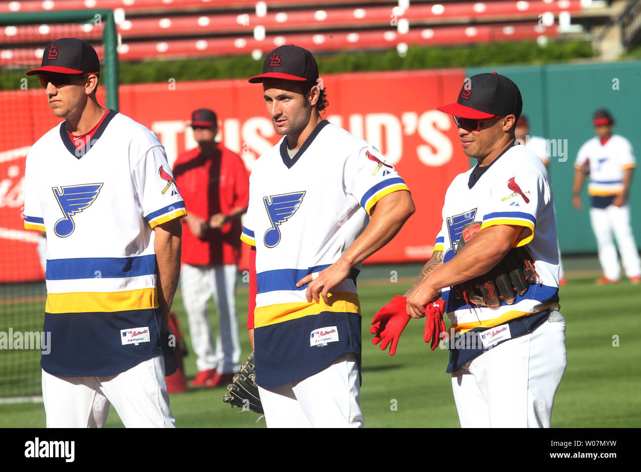 St. Louis Cardinals Cardinals players (L to R) Stephen Piscotty, Pete Kozma  and Kolten Wong watch batting practice while wearing St. Louis Blues jerseys  on St. Louis Blues Night before a game