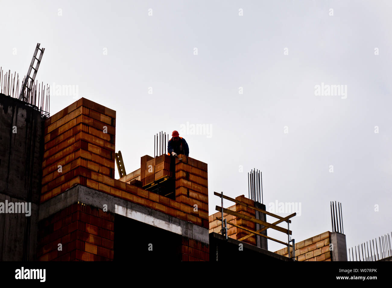 construction laborer at a construction site, working on the wall of a multi-storey residential building Stock Photo