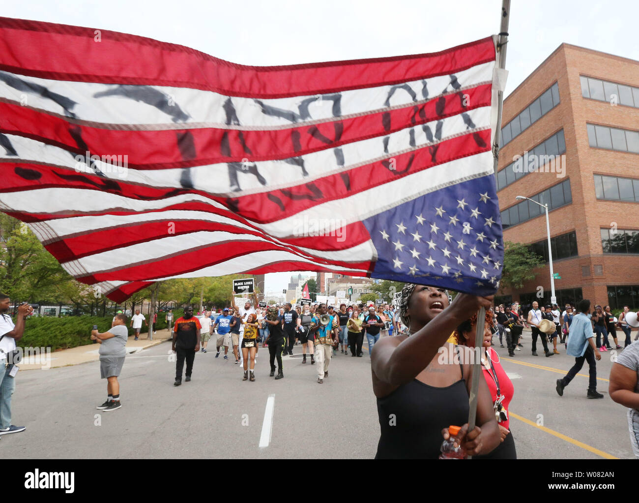 A woman carries an American flag upside down during a peaceful protest outside of St. Louis Metropolitian Police Headquarters in St. Louis on September 17, 2017. A non-guilty verdict of a former white St. Louis policeman in the 2011 shooting of a black man in St. Louis has resulted in two nights of peaceful marching eventually turning violent. Jason Stockley was acquitted of first degree murder charges in the fatal shooting of Anthony Lamar Smith on Dec. 11, 2011 following a high-speed chase. Police have made nearly 50 arrests while a score of businesses have suffered broken windows.   Photo b Stock Photo