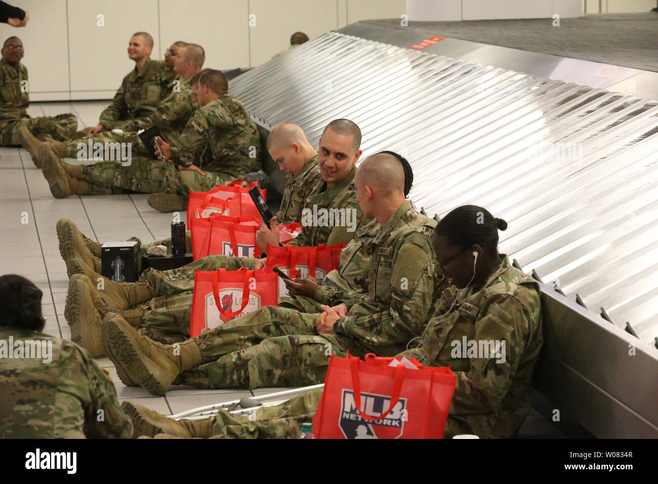 Soldiers from Fort Leonard Wood use the baggage carousel as support as they wait for their flights during Holiday Block Leave at St. Louis-Lambert International Airport in St. Louis on December 21, 2017. Nearly 4,000 men and women from the army training facility will board airplanes to go home for two weeks to celebrate the Christmas holidays. Photo by Bill Greenblatt/UPI Stock Photo