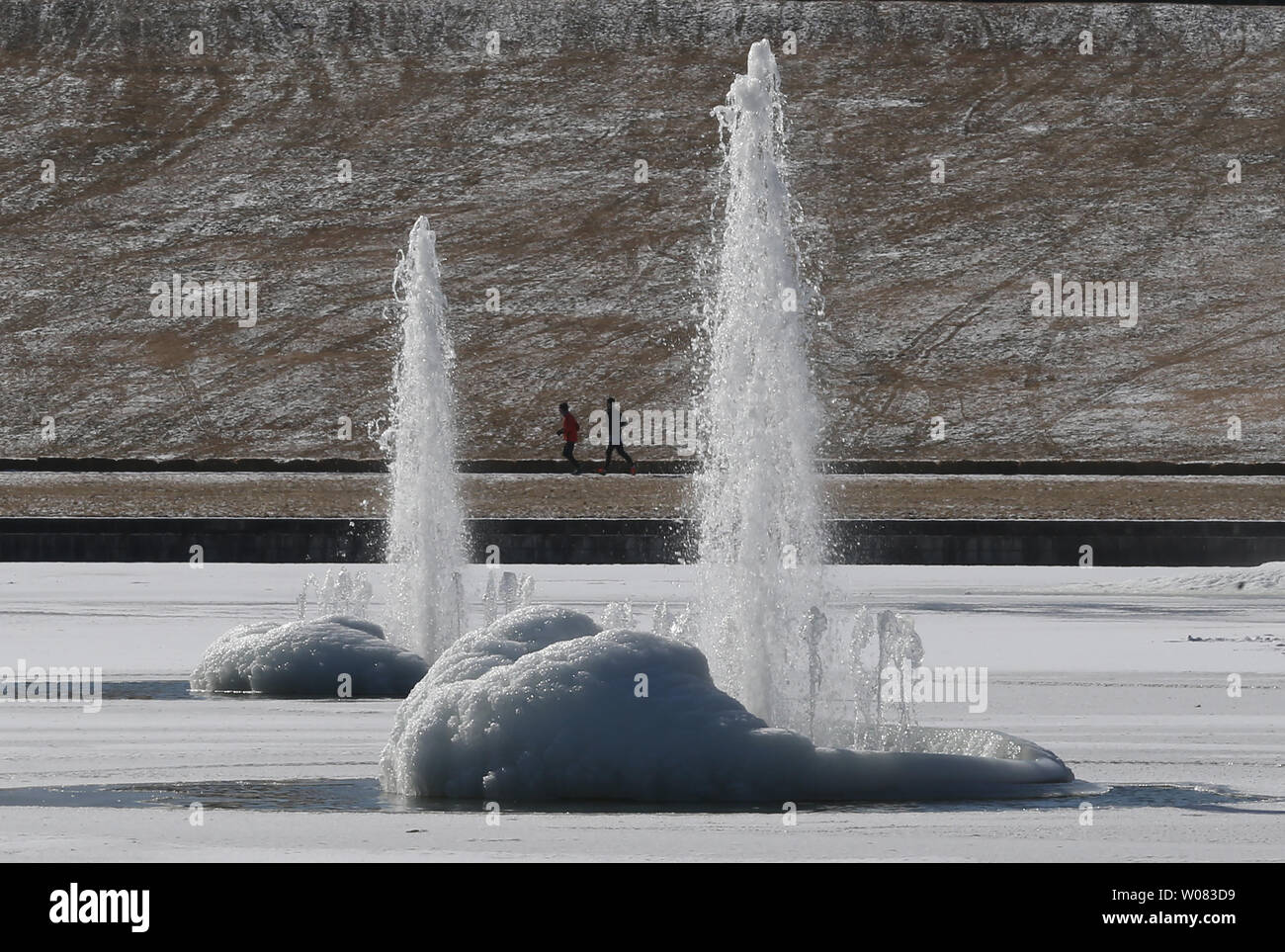 joggers run past the semi frozen fountains at the base of Art HIll as temperatures reach a high of 24 degrees in St. Louis on January 17, 2018. Forecasters predict temperatures in St. Louis may reach into the 50's for the weekend. Photo by Bill Greenblatt/UPI Stock Photo