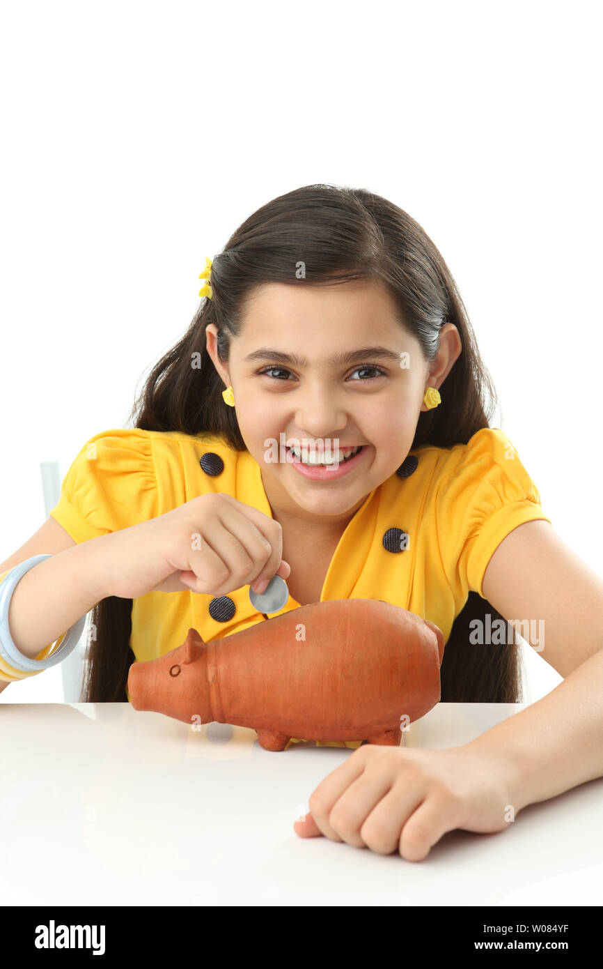Girl inserting coin into a piggy bank and smiling Stock Photo - Alamy