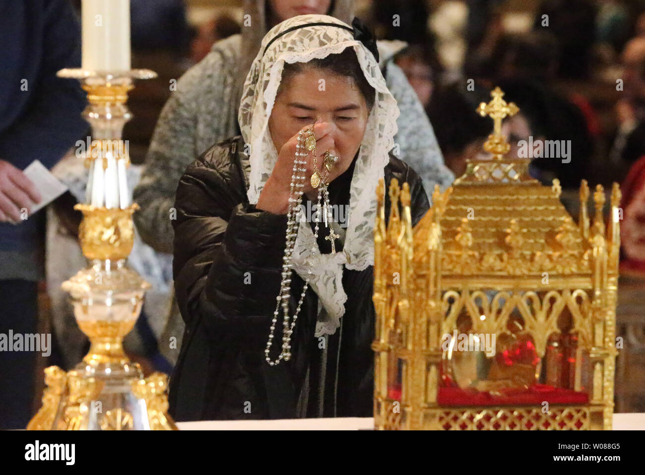 A parishioner holds holy beads in front of the Heart of a Priest display at the Cathedral Basilica of Saint Louis in St. Louis on March 15, 2019. St. John Vianney’s incorrupt heart is considered a major, first-class relic. The saint’s heart has resisted decay for more than 150 years. A relic like the incorrupt heart offers a tangible reminder of communion with the holy men and women who have gone before, offering strength to follow their example of faithful living. St. John Vianney, popularly known as the Cure? of Ars, is considered a model of priestly generosity, purity and prayerfulness. Bor Stock Photo