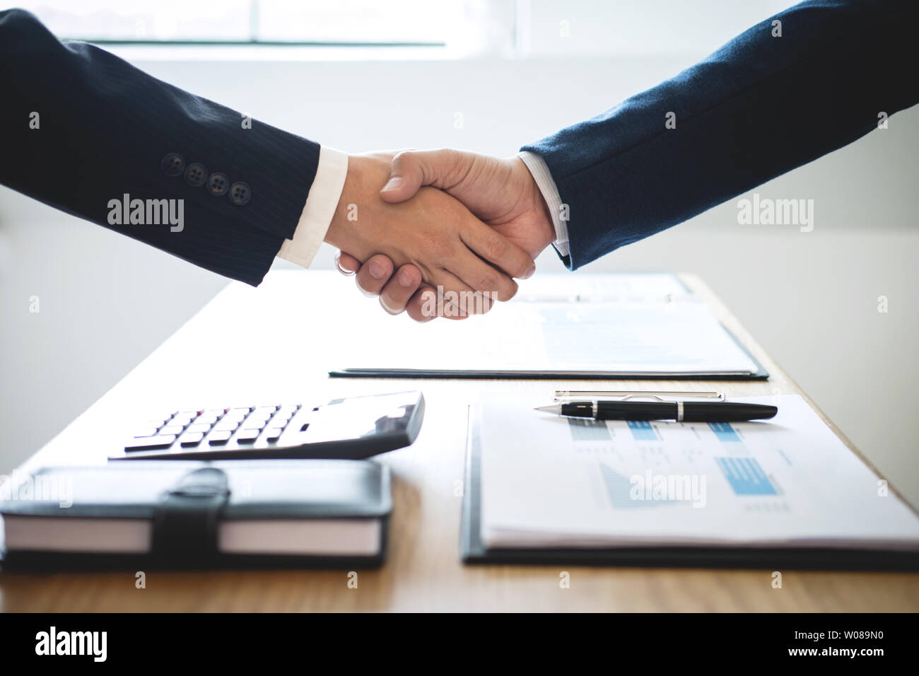 Finishing up a meeting, handshake of two happy business people after contract agreement to become a partner, collaborative teamwork. Stock Photo