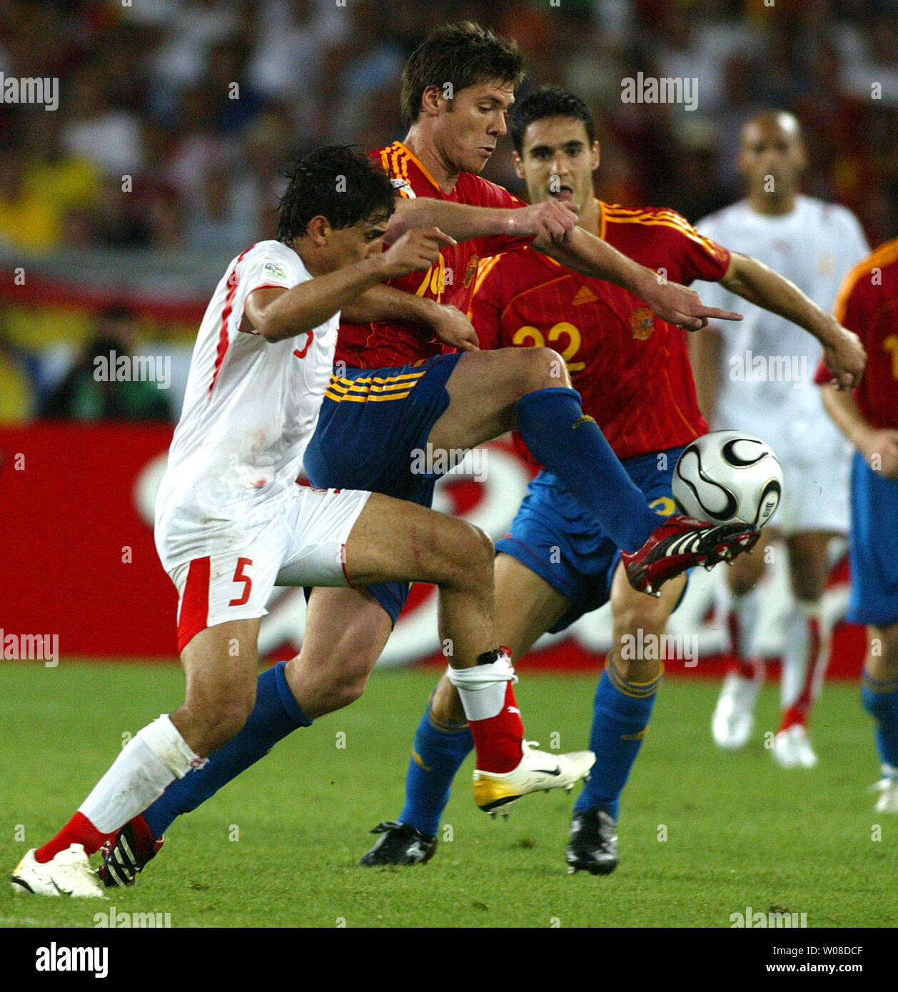 Xabi Alonso (14) from Spain dominates Tunisia's players and resists attacks from Zied Jaziro (5) in World Cup soccer action in Stuttgart, Germany on June 19, 2006. Spain defeated Tunisia 3-1.  (UPI Photo/Arthur Thill) Stock Photo