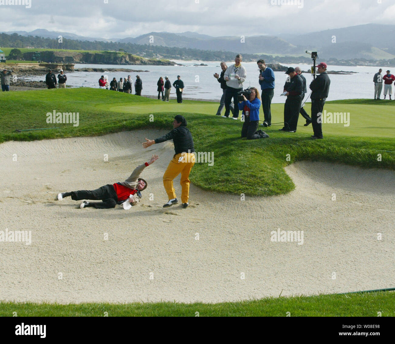George Lopez drags sportscaster Bob Murphy into a sand trap on the 18th green  during a celebrity golf challenge February 4, 2004 at Pebble Beach, CA.    (UPI PHOTO/TERRY SCHMITT) Stock Photo