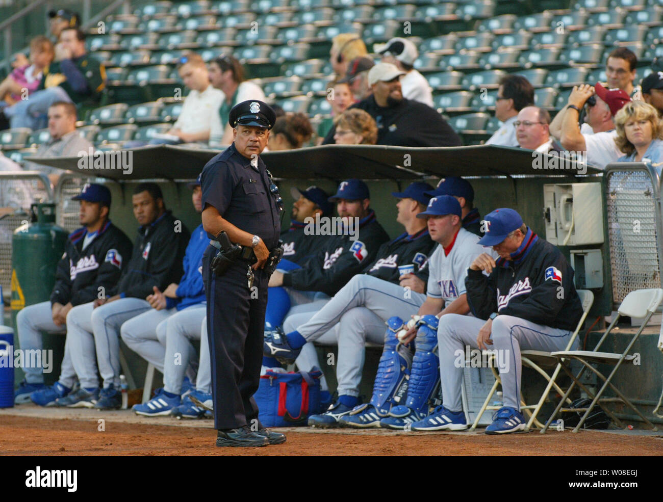 Oakland Police officer Rudy Villegas stands guard by  the Texas Rangers bullpen during a game against the Oakland Athletics on September 14, 2004 in Oakland, CA. Extra security was added to the game after an altercation the night before between Rangers players and fans saw a chair thrown, a fan bloodied and Texas Rangers relief pitcher Frank Francisco  booked by the Oakland Police for aggravated battery.  (UPI Photo/Bruce Gordon) Stock Photo