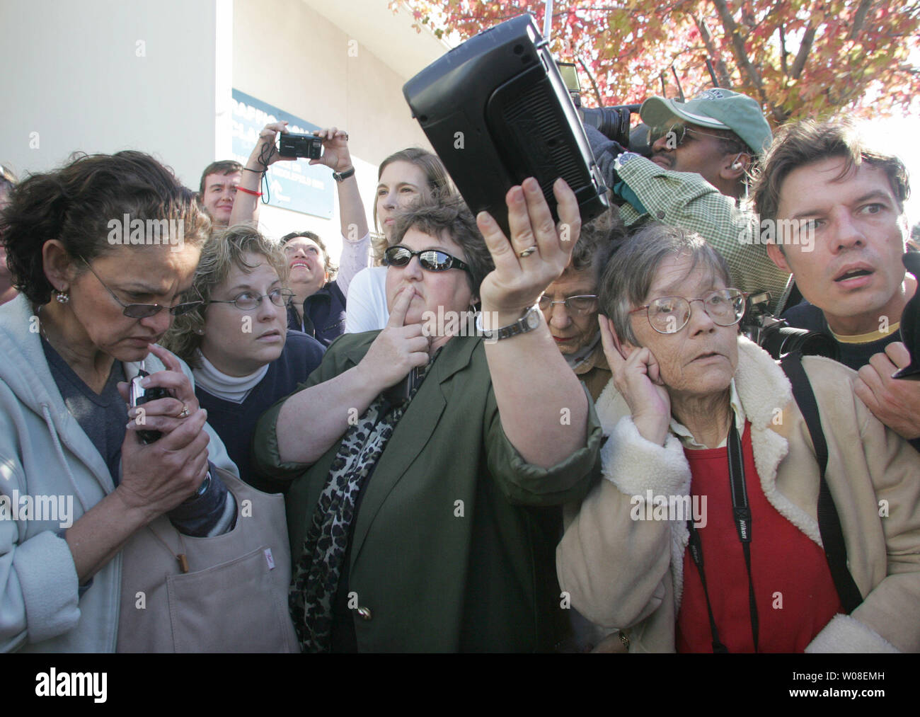 Fran Corbet signals for spectators to be quiet as they gather around her radio to hear the live feed from the  courtroom where the verdict in the Scott Peterson murder trial is about to be announced,  as many people gather on the street outside the courthouse in Redwood City, California on November 12, 2004. Peterson was found guilty of murdering his wife Laci and unborn son.  (UPI Photo/Terry Schmitt) Stock Photo