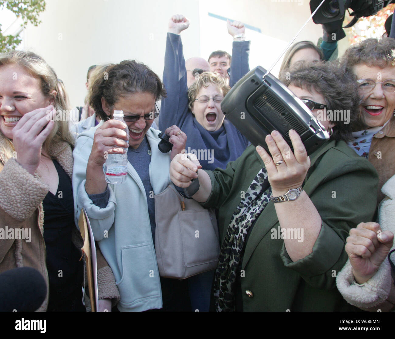 Spectators gathered around a radio react to the verdict in the Scott Peterson murder trial on the street outside the courthouse in Redwood City, California on November 12, 2004. Peterson was found guilty of murdering his wife Laci and unborn son.  (UPI Photo/Terry Schmitt) Stock Photo