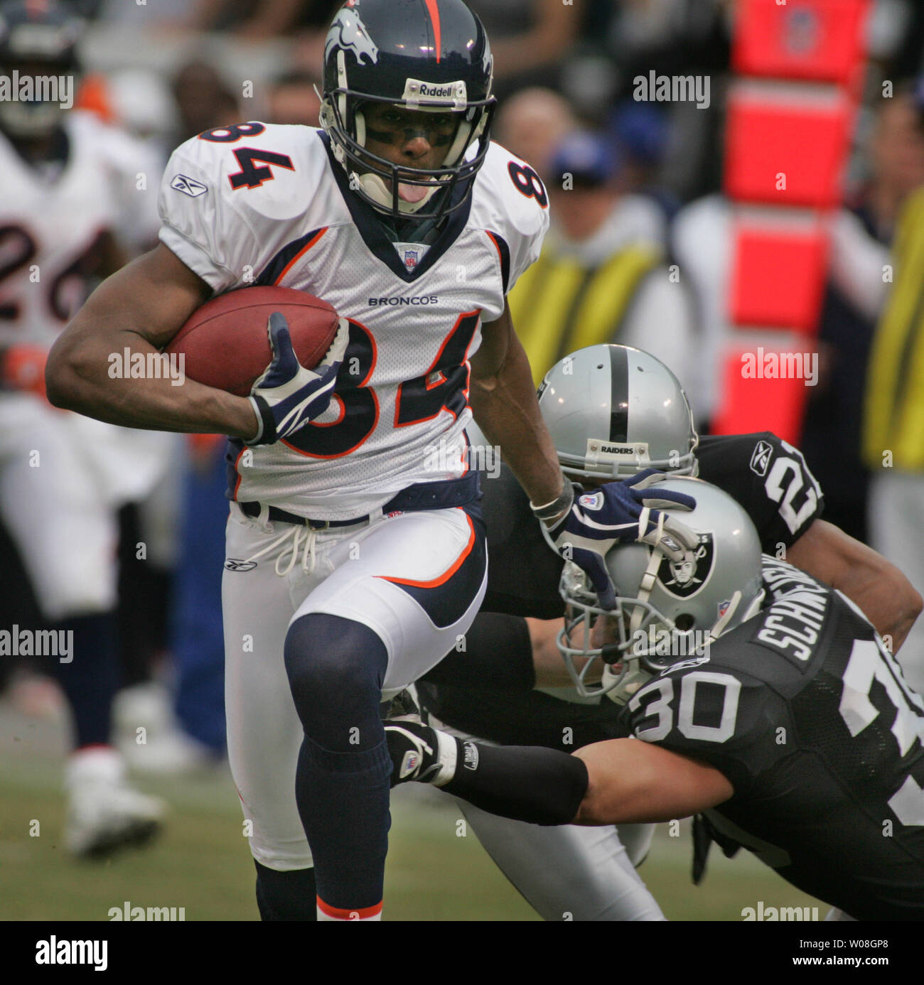 Denver Broncos Javon Walker (84) shoves off Oakland Raiders Stuart  Schweigert (30) as he takes a short Jake Plummer pass 39 yards for a TD in  the first quarter at McAfee Coliseum