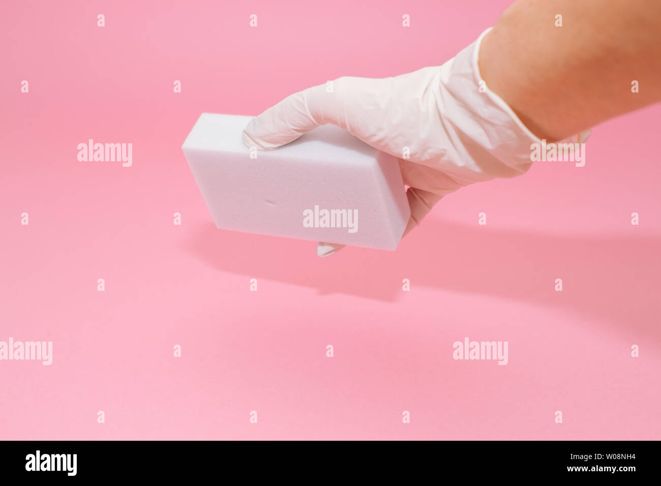 Human hand in white glove holds a white melamine household sponge for ...