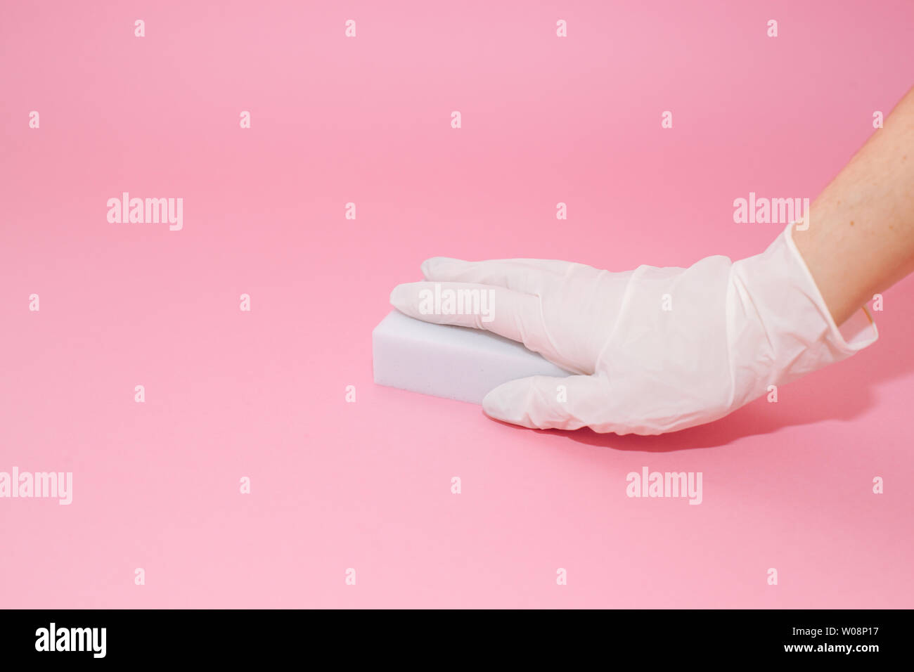 Human hand in white glove holds a white melamine household sponge for ...