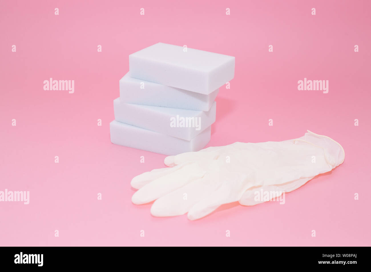 Human hand in white glove holds a white melamine household sponge for ...