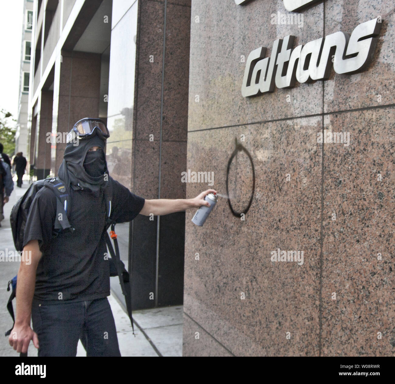 A vandal spray paints the Caltrans building during a May Day protest in Oakland, California on May 1, 2012.  Demonstrators closed streets and clashed with police.   UPI/Terry Schmitt Stock Photo