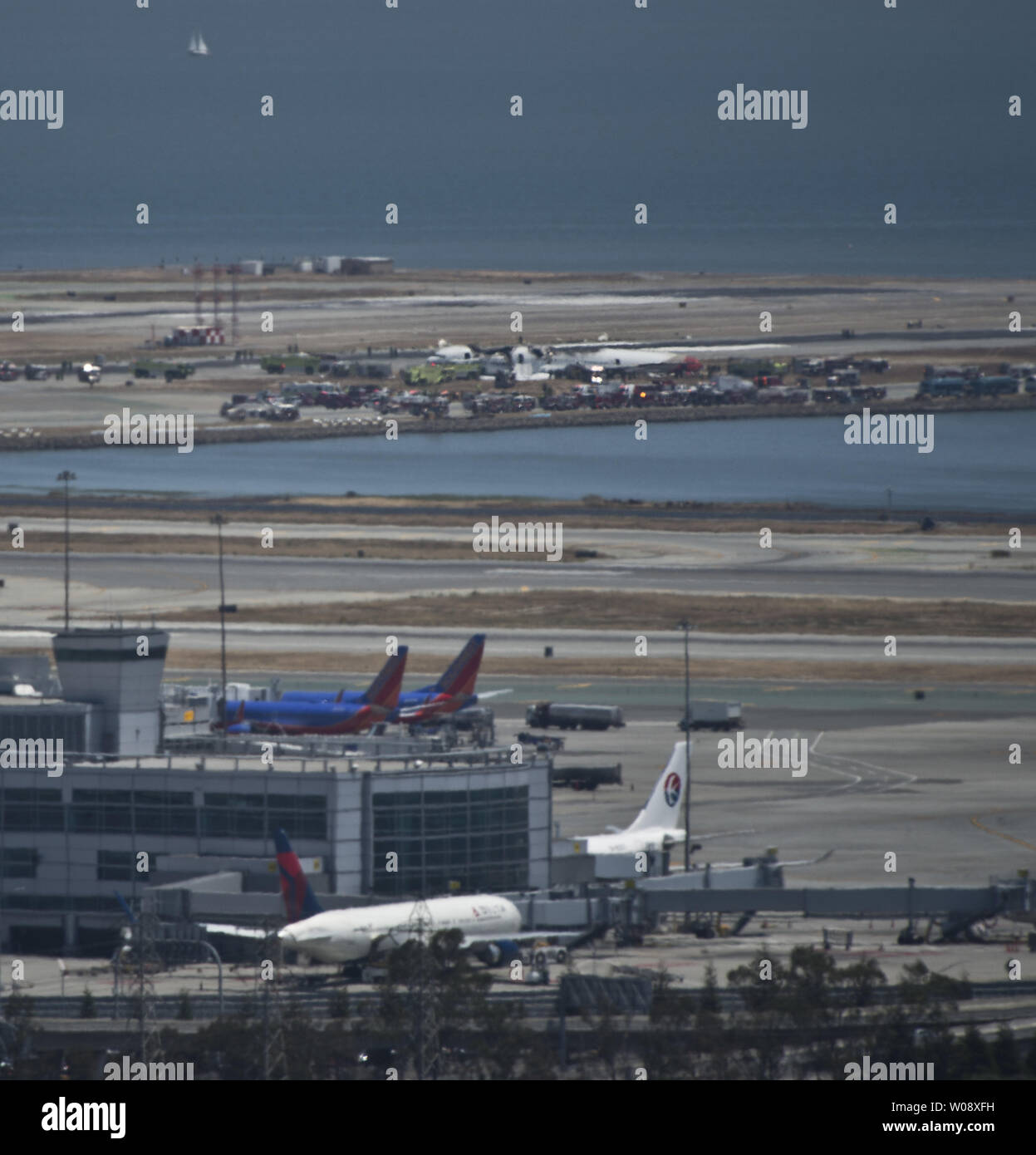 Emergency vehicles surround the remains of an Asiana Air Boeing 777 on the runway at San Francisco International Airport (background) after it crashed on landing in San Francisco on July 6, 2013. The plane was arriving from Seoul.    UPI/Terry Schmitt Stock Photo