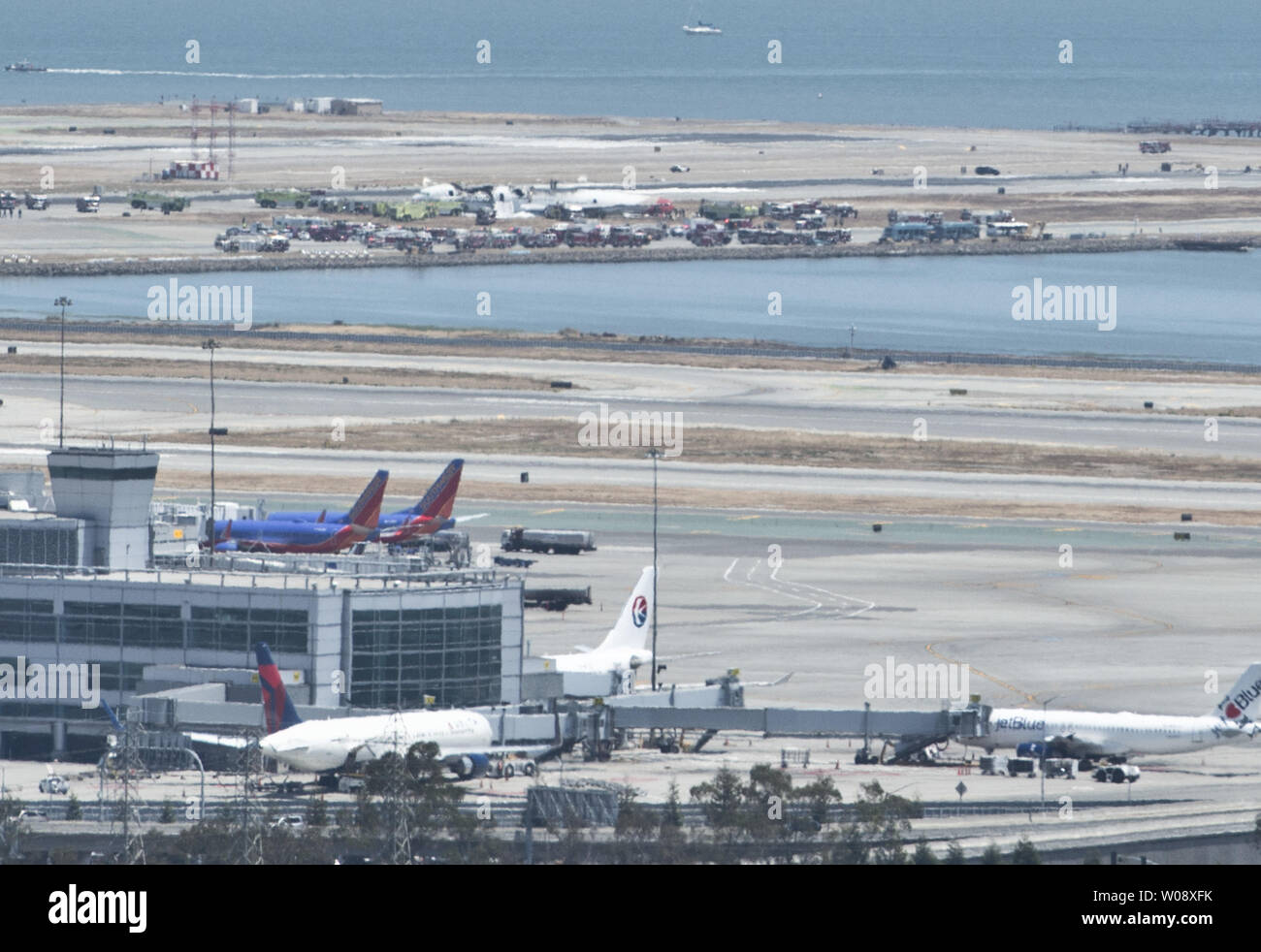 Emergency vehicles surround the remains of an Asiana Air Boeing 777 (background) on the runway at San Francisco International Airport after it crashed on landing in San Francisco on July 6, 2013. The plane was arriving from Seoul.    UPI/Terry Schmitt Stock Photo