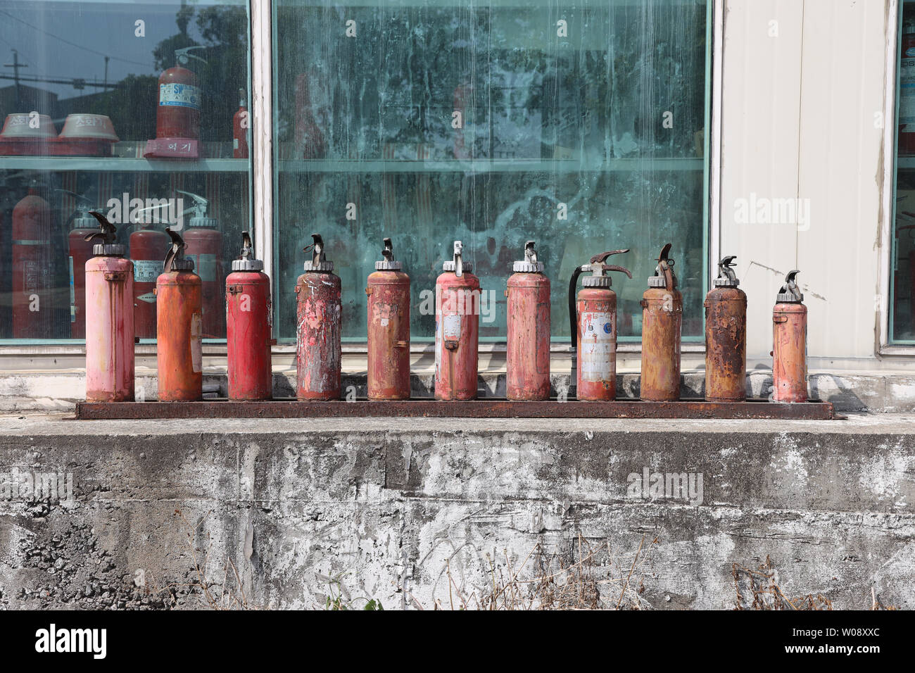A row of old fire extinguishers in front of a shop window with fire