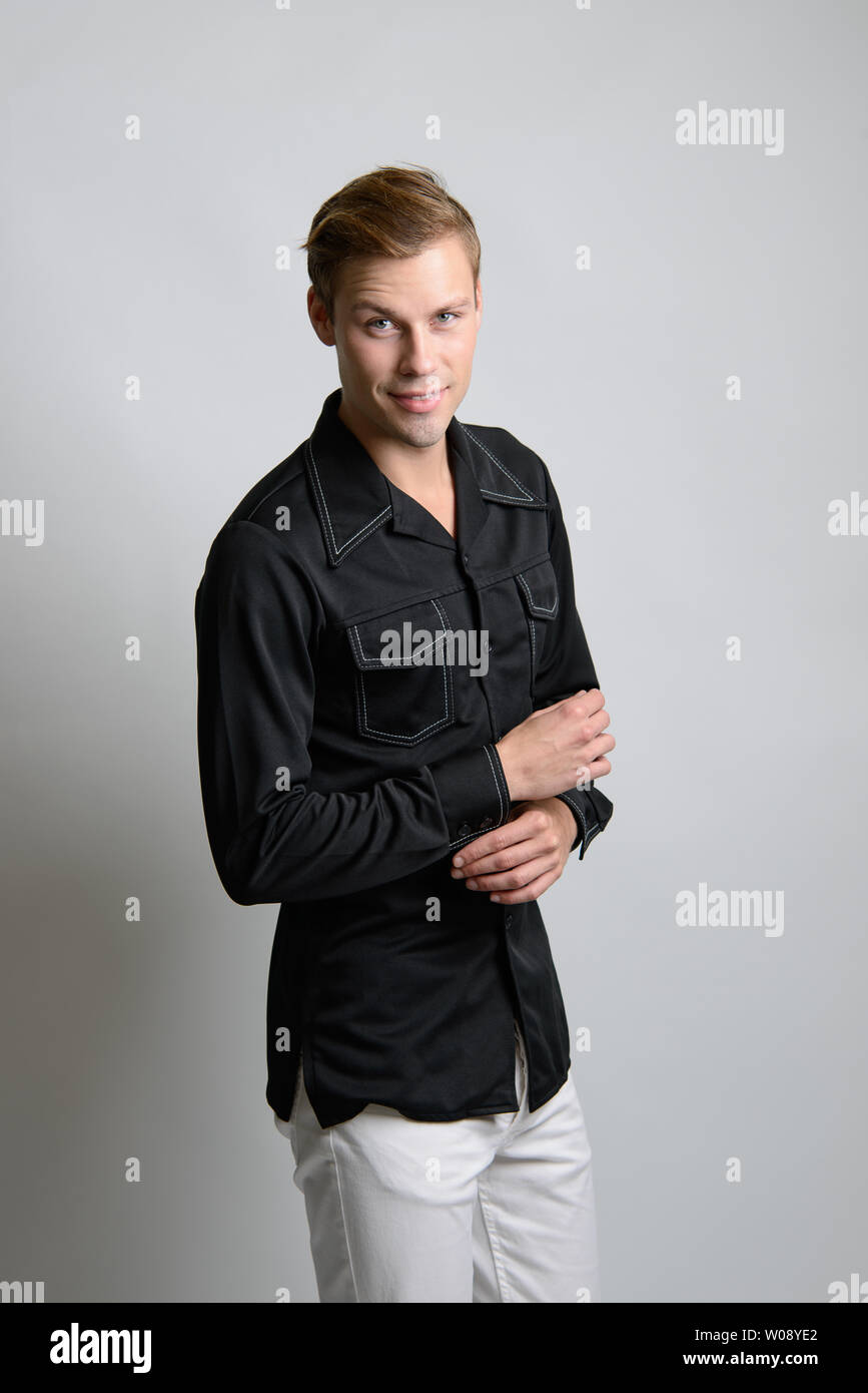 A Brown hair Caucasian male model poses in vintage clothing outfit, he wears a black shirt, a men's vintage fashion editorial. Stock Photo
