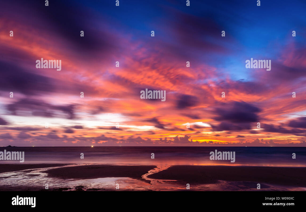 Blurry movement of colorful cloudy twilight sky reflecting to Phuket beach, Thailand at sunset. Stock Photo
