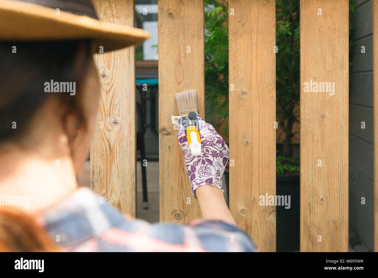 Woman with a paintbrush painting wooden terrace railings. Outdoor shot Stock Photo