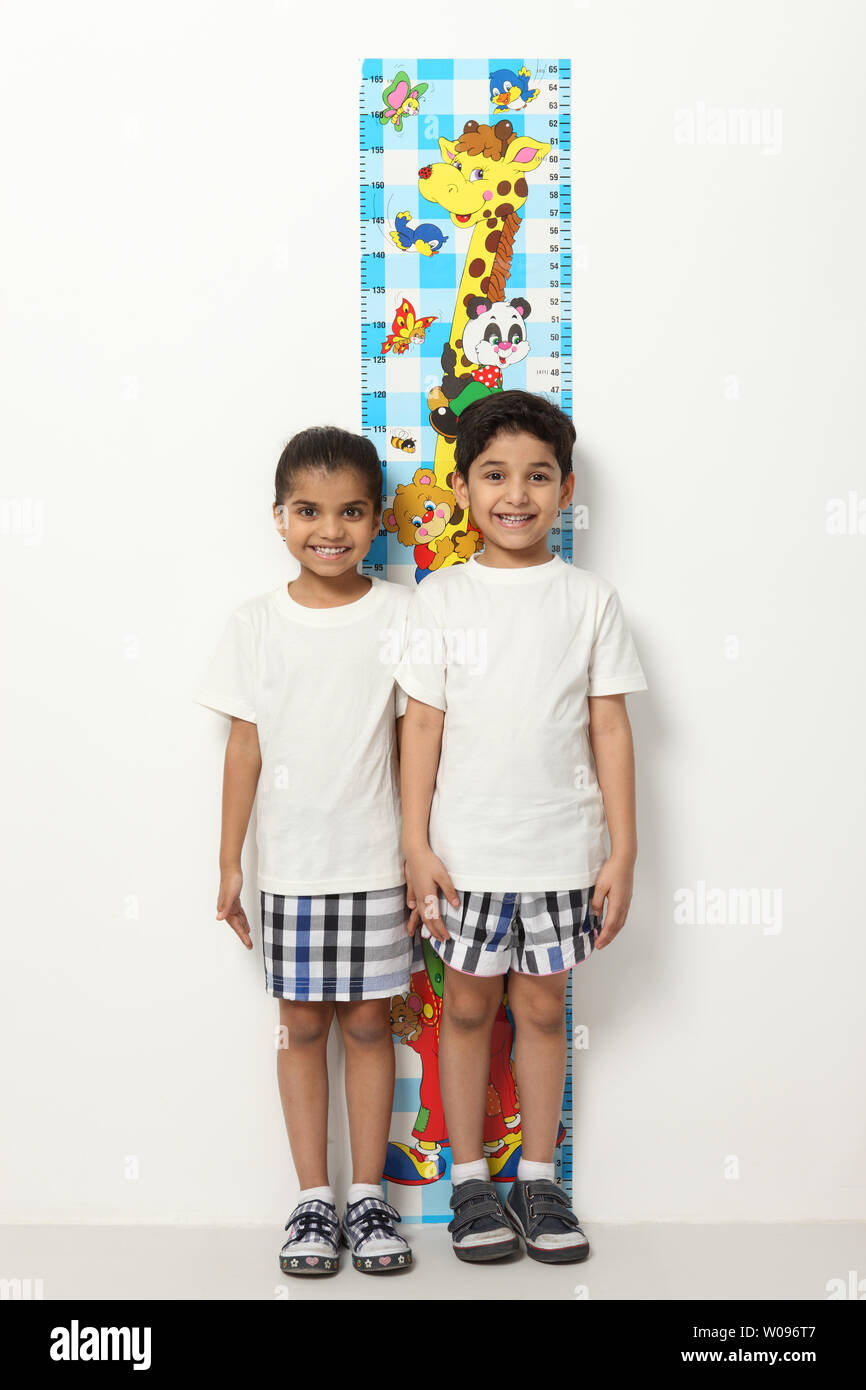 Portrait of two children measuring their heights Stock Photo Alamy