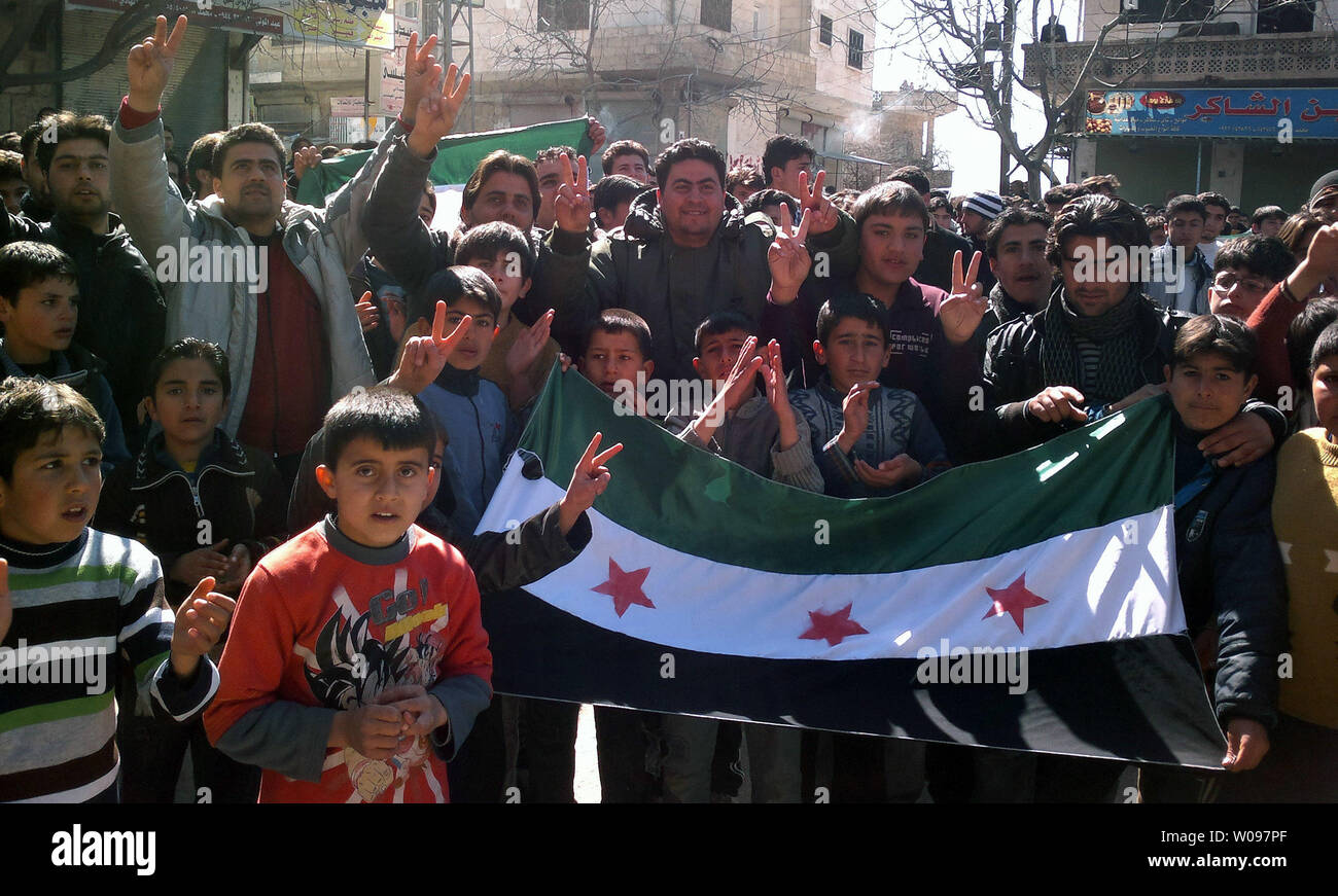 Demonstrators hold  Syrian opposition flag during a protest against Syria's President Bashar al-Assad in Kafranbel near Idlib, in Syria, February 24, 2012. Syrian troops shelled the rebel stronghold in Homs for the 22nd straight day, after a pause allowed relief workers to evacuate some civilians, monitors said.  UPI Stock Photo