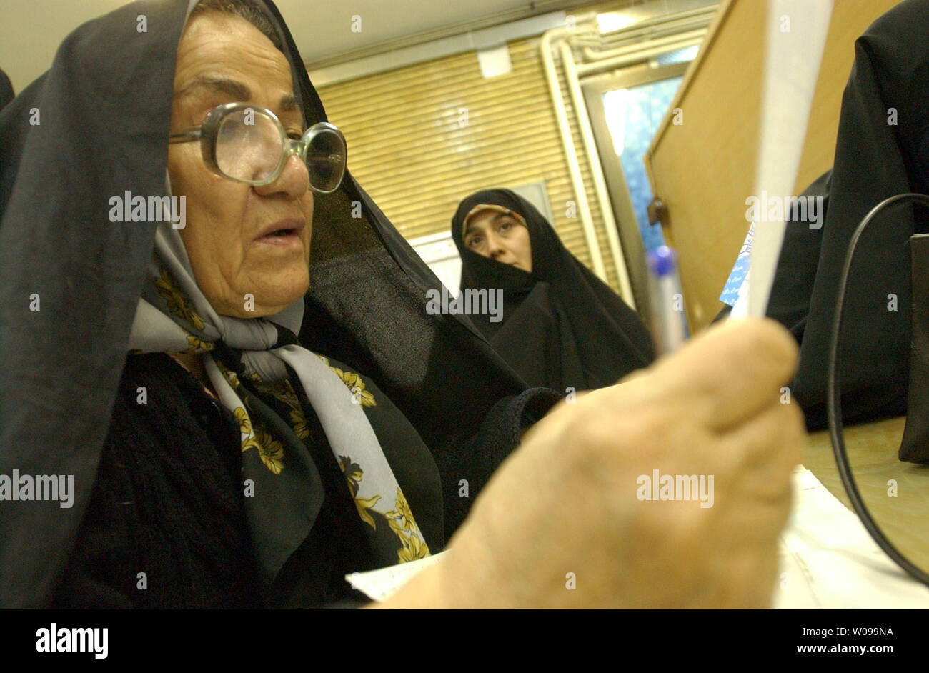 An Iranian woman checks his ballot before casting it in national parliamentary elections in Tehran, Iran Friday, Feb. 20, 2004. Hardline candidates are expected to sweep the vote, as Iran's pro-reform parties have urged a mass boycott after the conservative theocracy banned more than 2,400 candidates .   (UPI Photo/Ali Khaligh) Stock Photo