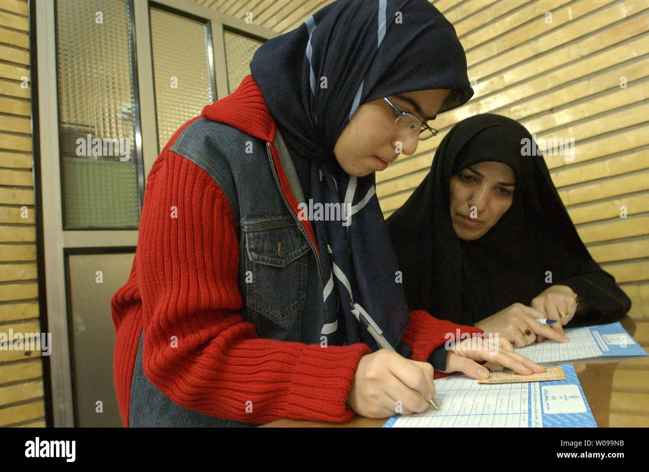 An Iranian woman helps her daughter, age 15, with her ballot before casting it in national parliamentary elections in Tehran, Iran Friday, Feb. 20, 2004.  Hardline candidates are expected to sweep the vote, as Iran's pro-reform parties have urged a mass boycott after the conservative theocracy banned more than 2,400 candidates.   (UPI Photo/Ali Khaligh) Stock Photo