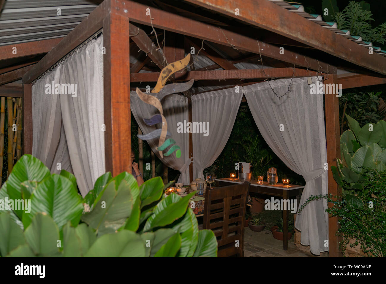 Stylish dining setting in evening and candle light in garden gazebo