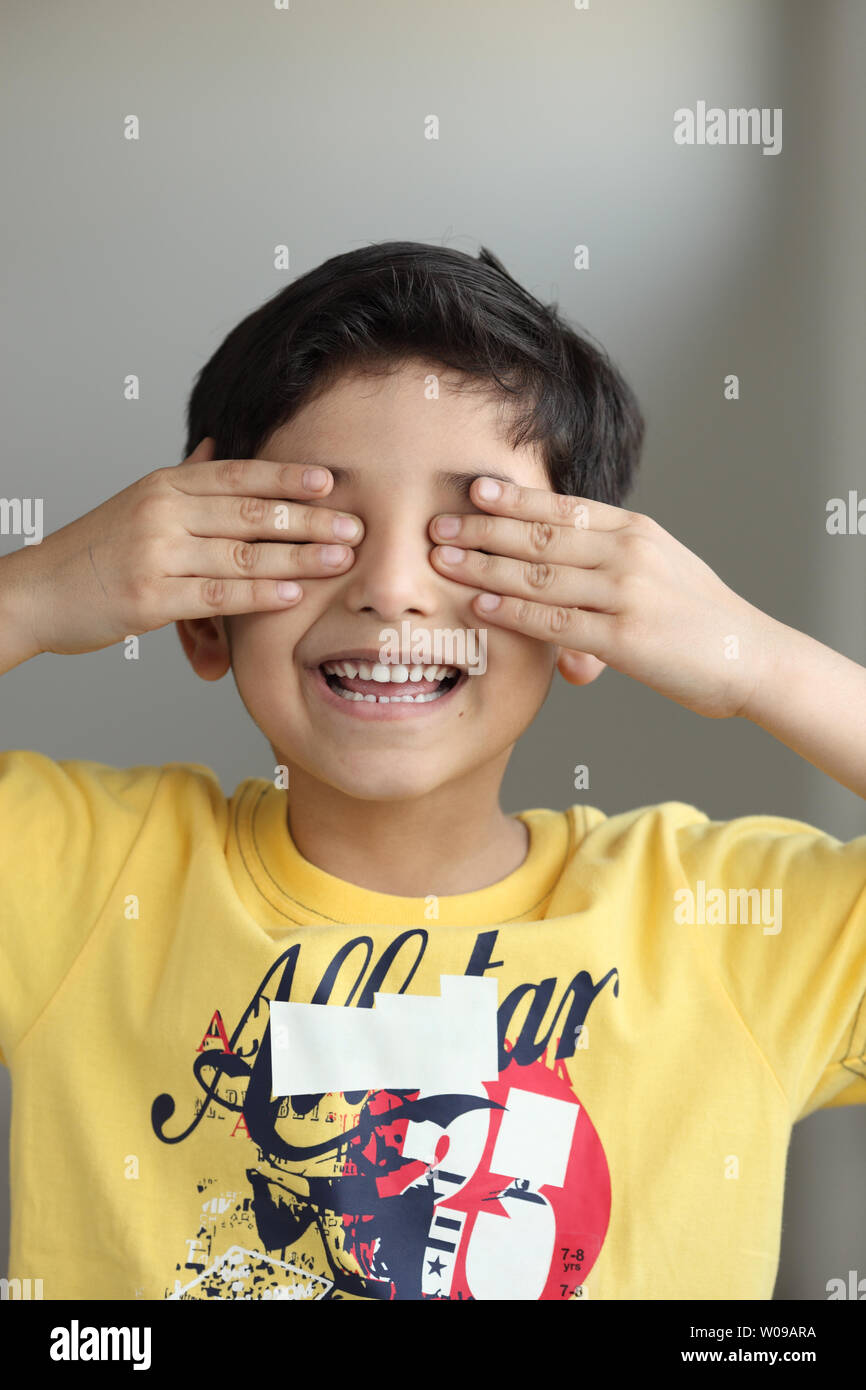 Indian boy covering his eyes with his hands Stock Photo - Alamy