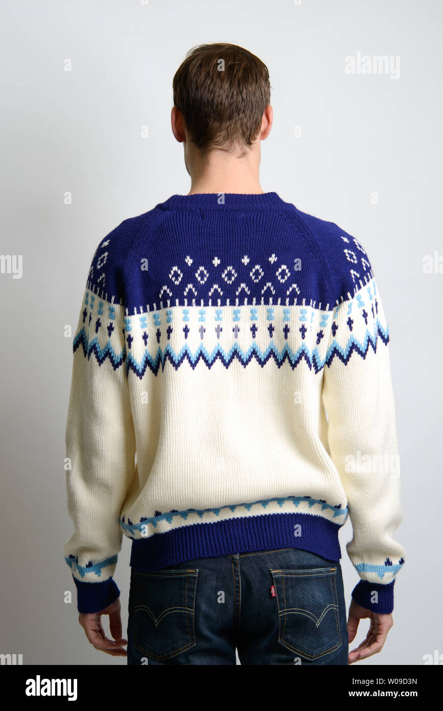 A Brown hair Caucasian male model poses in vintage sweater, back facing camera, a men's vintage fashion editorial. Stock Photo