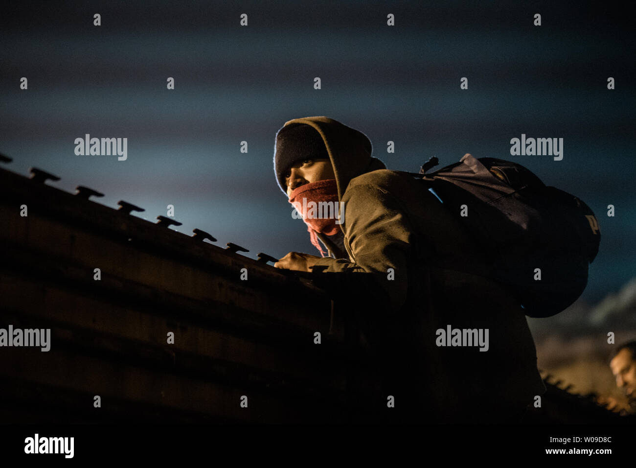 A young man traveling with the migrant caravan looks over the fence to see if he can see the U.S. Border Patrol as he and others attempt to cross the border fence in Tijuana, Mexico on December 26, 2018.    The U.S. government is in a partial shutdown due to a funding argument about the border.   Photo by Ariana Drehsler/UPI Stock Photo