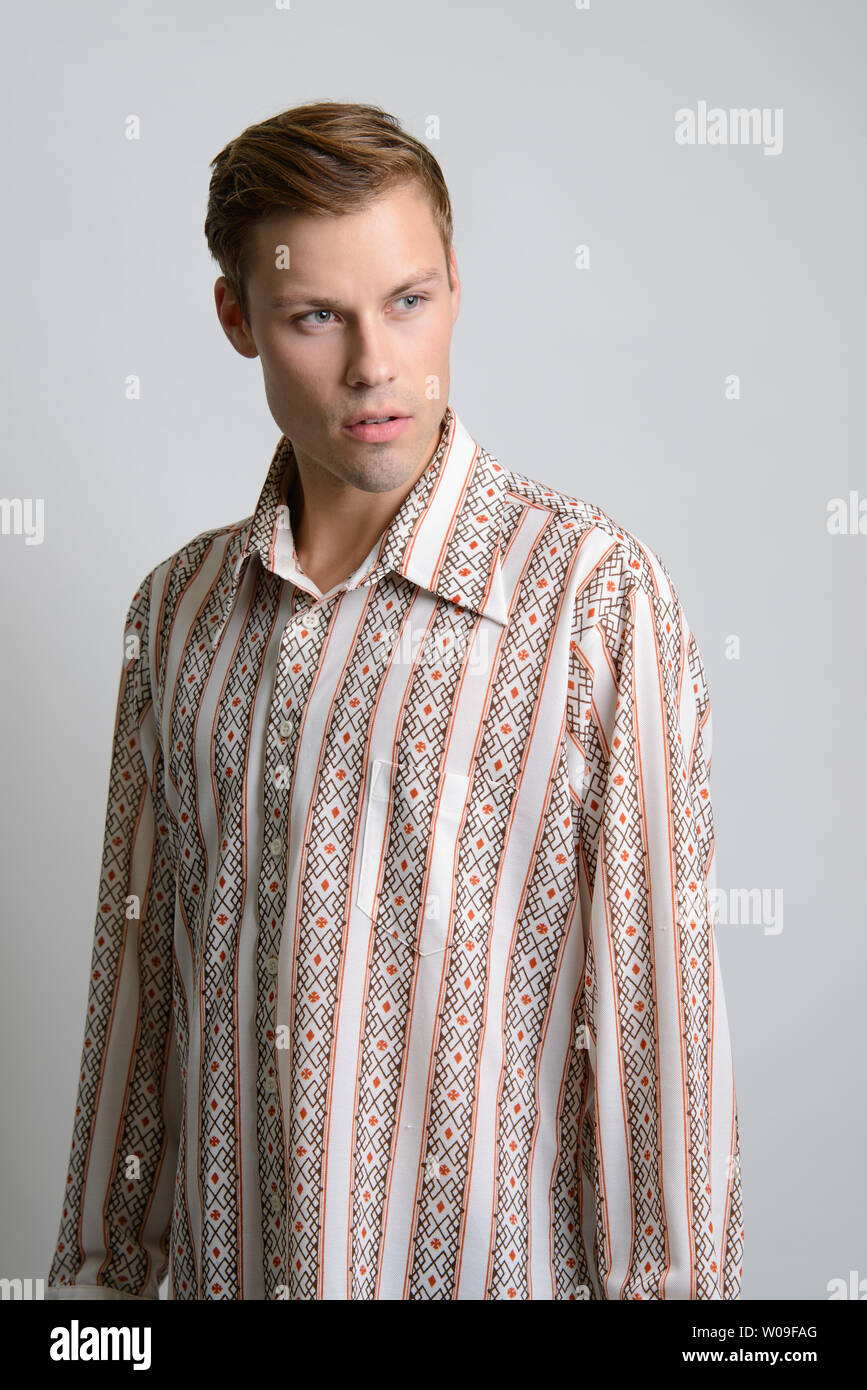 A Brown hair Caucasian male model poses in vintage stripe shirt, a men's vintage fashion editorial. Stock Photo