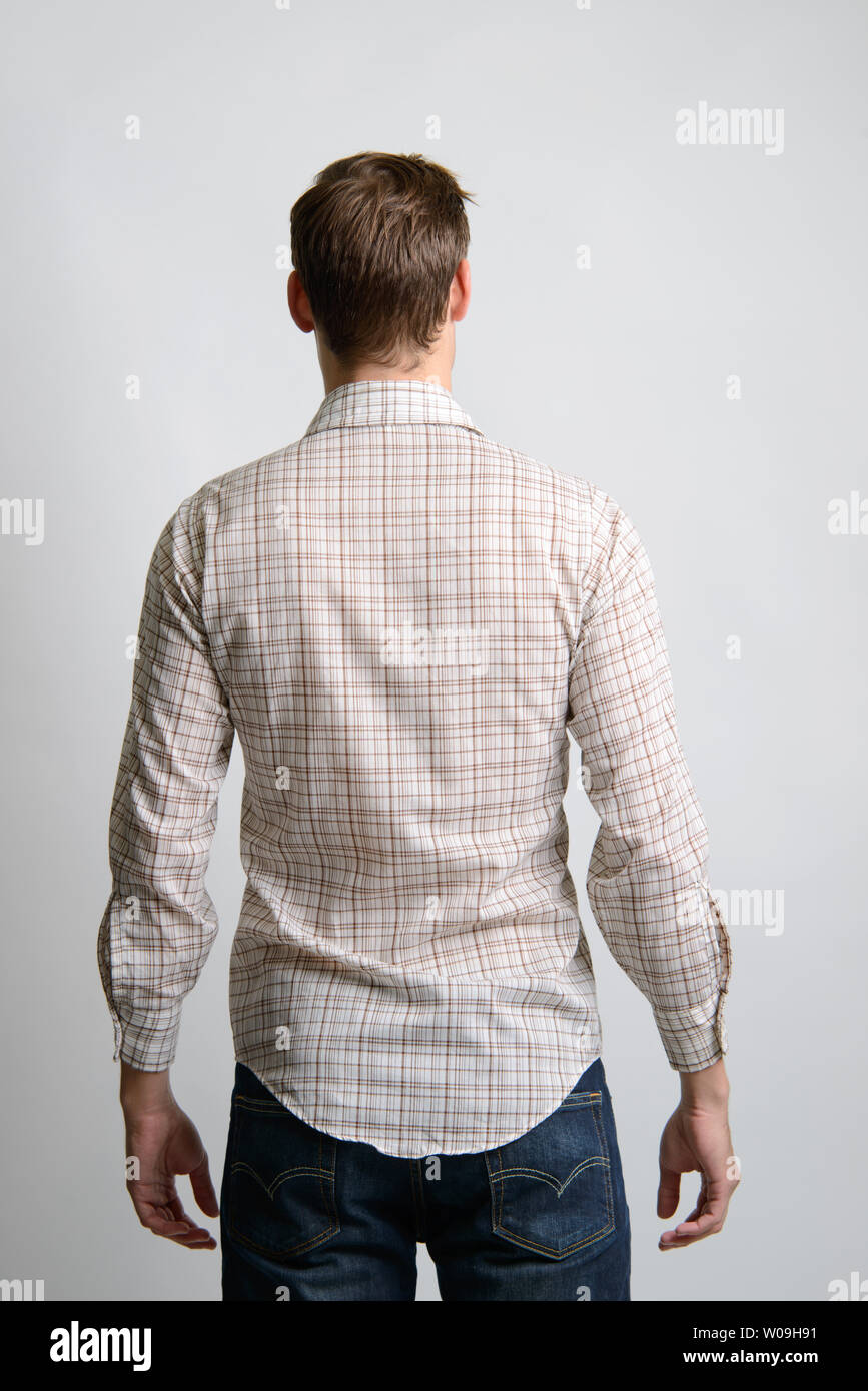 A Brown hair Caucasian male model poses in vintage brown plaid western shirt back facing camera. Stock Photo