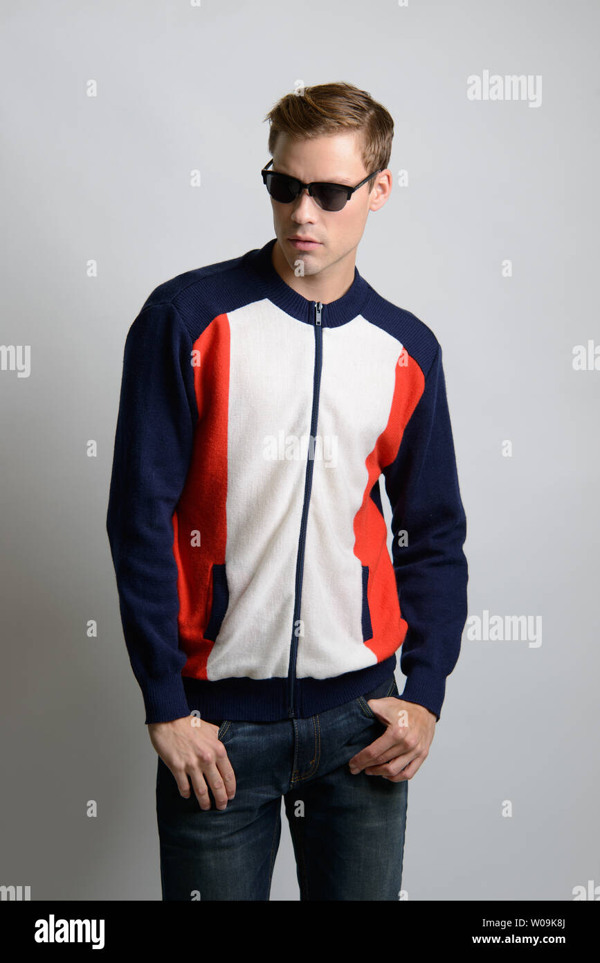 A Brown hair Caucasian male model in sunglasses poses in vintage sweater, vintage jacket, a men's vintage fashion editorial. Stock Photo