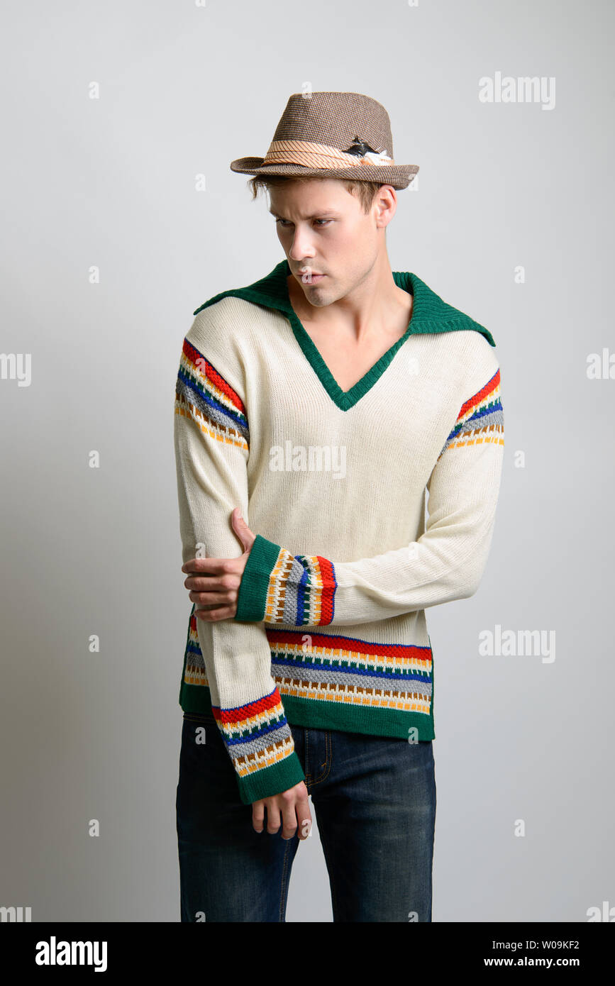 A Brown hair Caucasian male model wearing a brown fedora hat, poses in vintage sweater, a men's vintage fashion editorial. Stock Photo