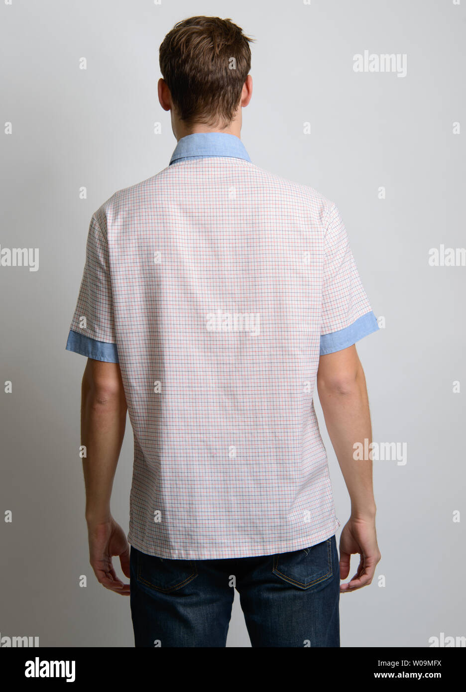 A Brown hair Caucasian male model back facing camera, poses in vintage shirt, 60s shirt, a vintage preppy style fashion editorial. Stock Photo