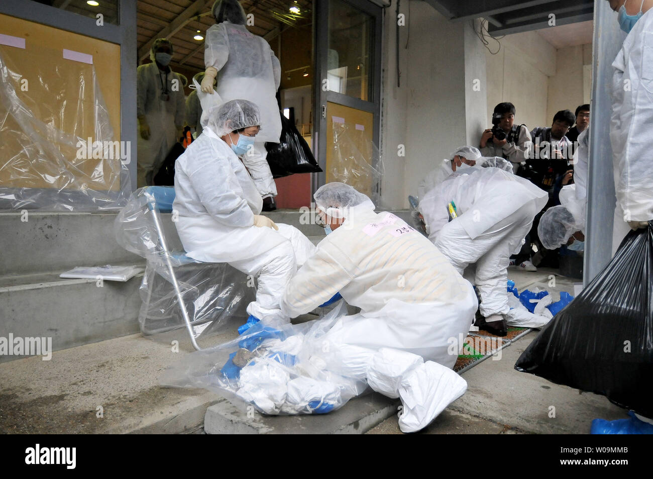 Evacuees take off cover for shoes after returning from a brief visit back to their homes  inside the restricted zone of a 20 km radius from the Fukushima Daiichi Nuclear Power Plant at the Furumichi gymnasium in Tamura, Fukushima prefecture, Japan, May 22, 2011.     UPI/Keizo Mori Stock Photo