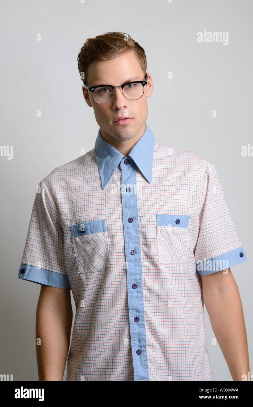 A Brown hair Caucasian male model poses in vintage shirt, 60s shirt, a vintage preppy style fashion editorial. Stock Photo