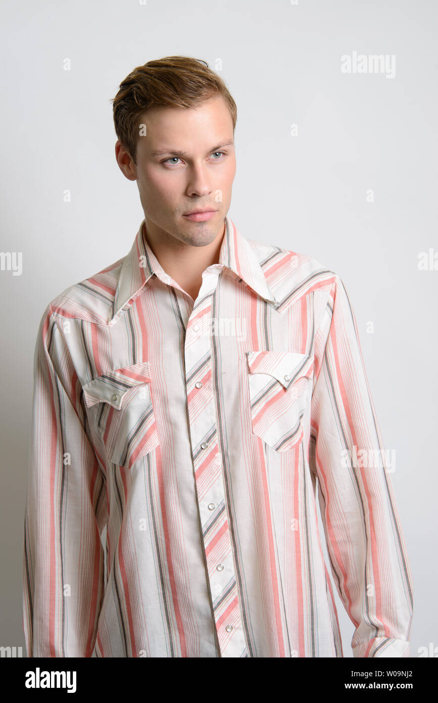 A Brown hair Caucasian male model poses in vintage stripe shirt, a men's vintage fashion editorial. Stock Photo
