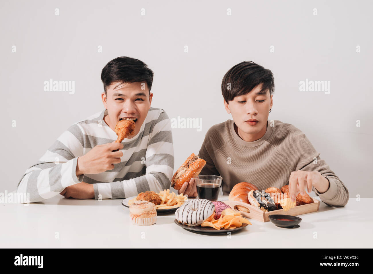 Two friends eating burgers. french fries, having fun and smiling Stock Photo