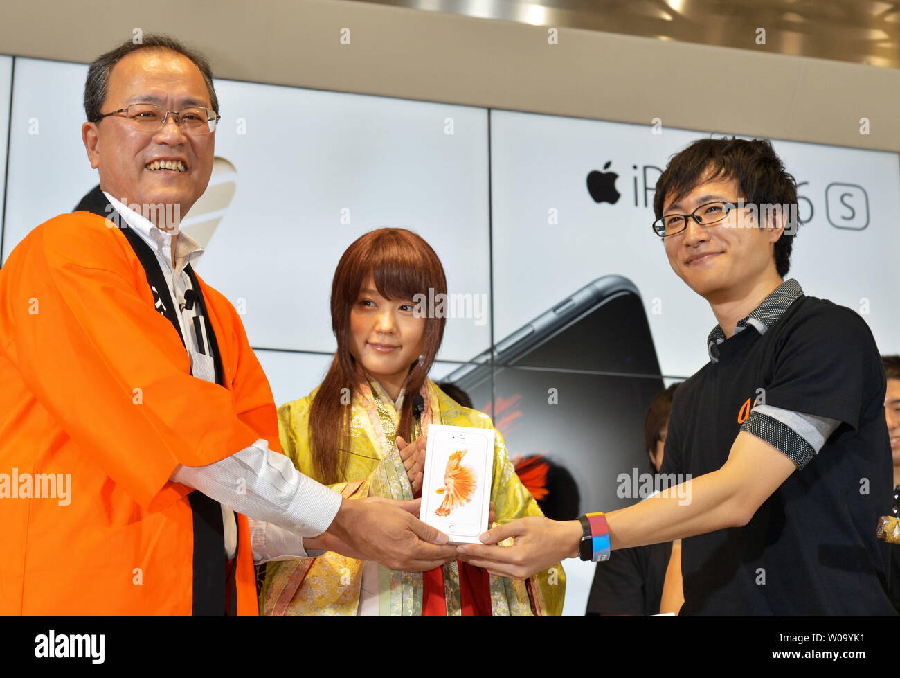 (L-R)Koji Tanaka, President of KDDI Corporation, Japanese actress Kasumi Arimura and first customer pose for pictures during launch day of new iPhone 6s and iPhone 6s Plus at the KDDI's au Shinjuku store in Tokyo, Japan, on September 25, 2015.     Photo by Keizo Mori/UPI Stock Photo