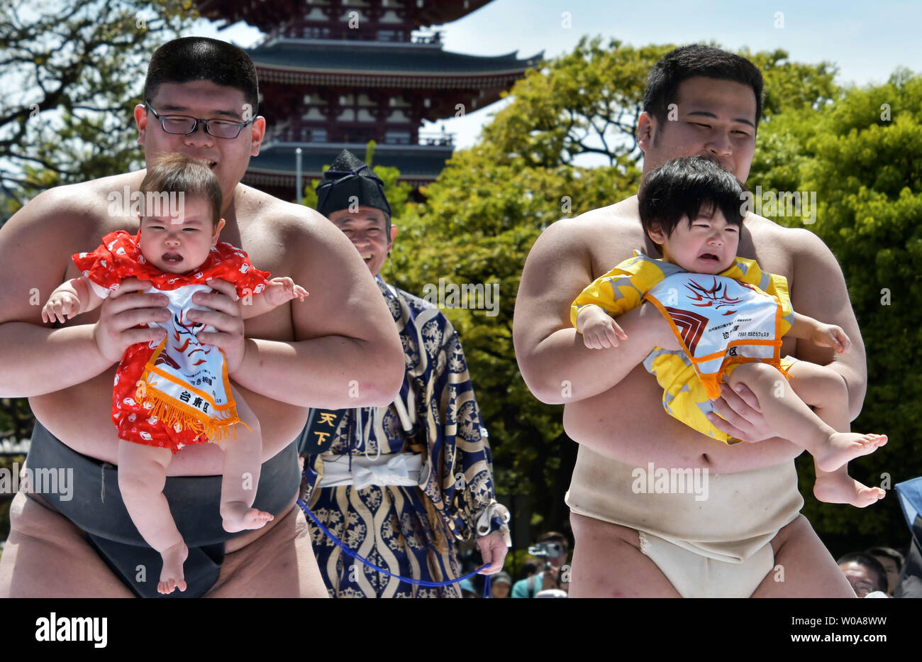 Babies held by an amateur sumo wrestler cry during the 